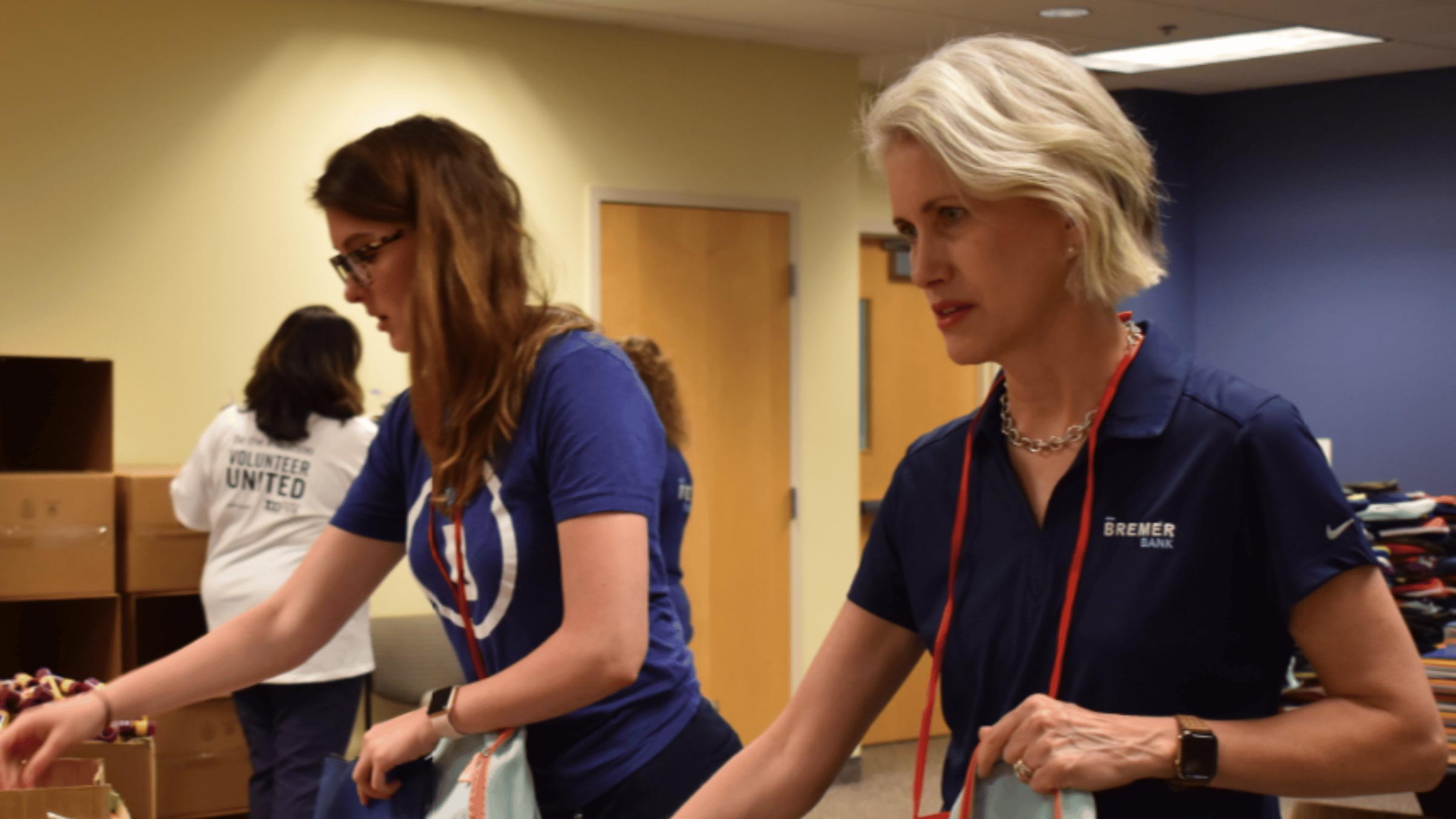 Two Bremer Bank volunteers pack backpacks together