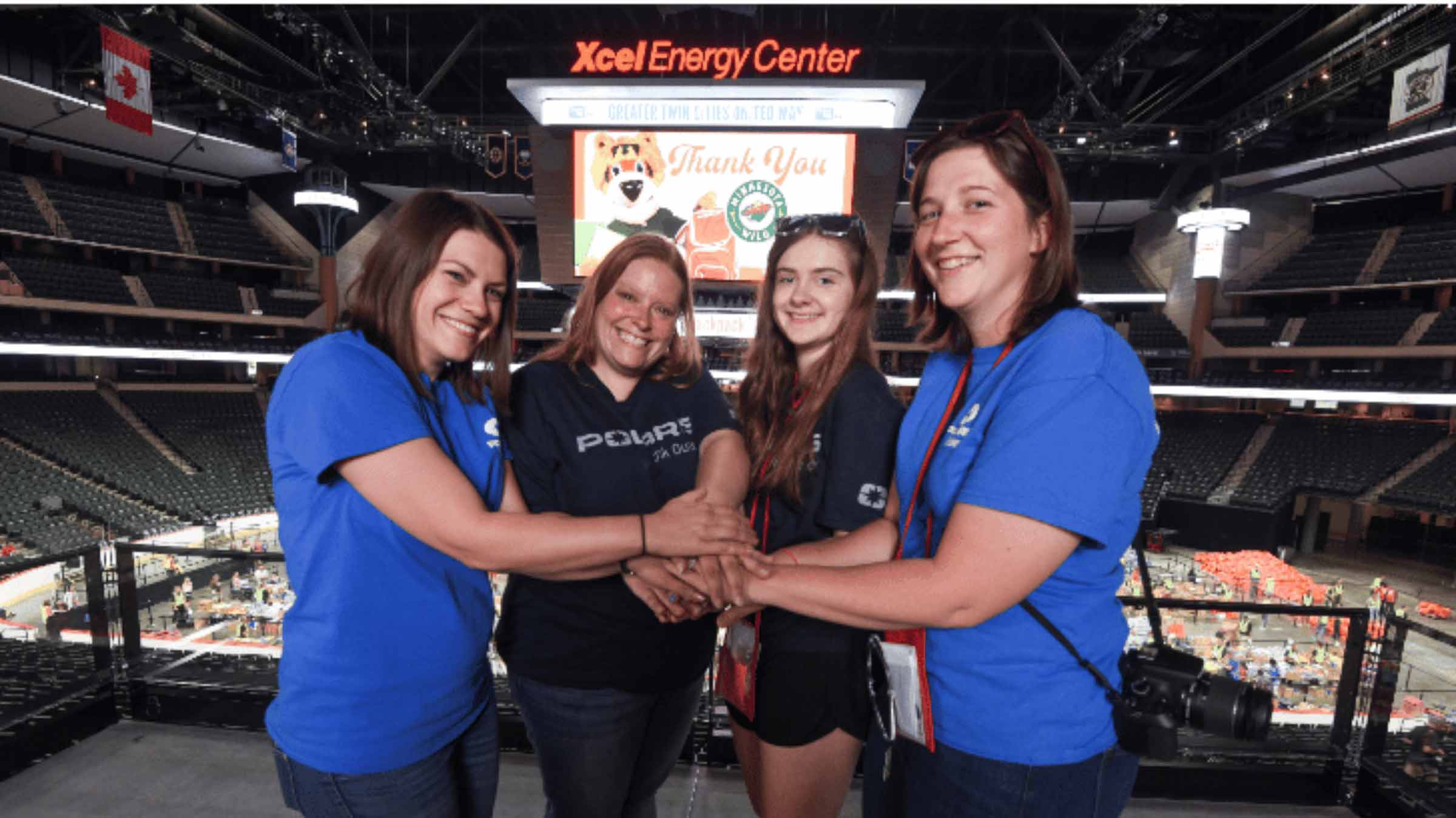A group of volunteers stands together in front of the Xcel Energy Center