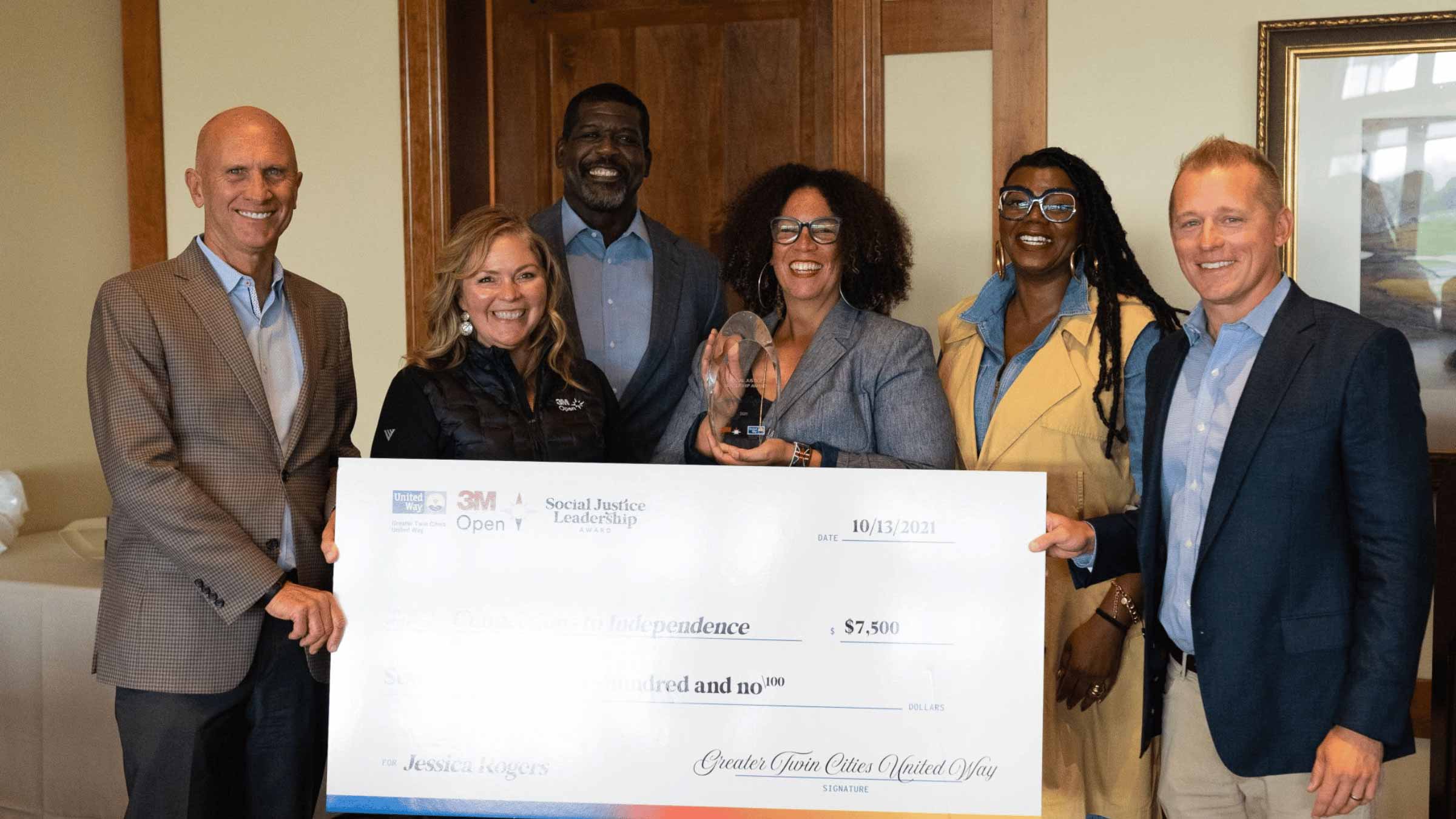 A group of people stand with a large check printed in front of them