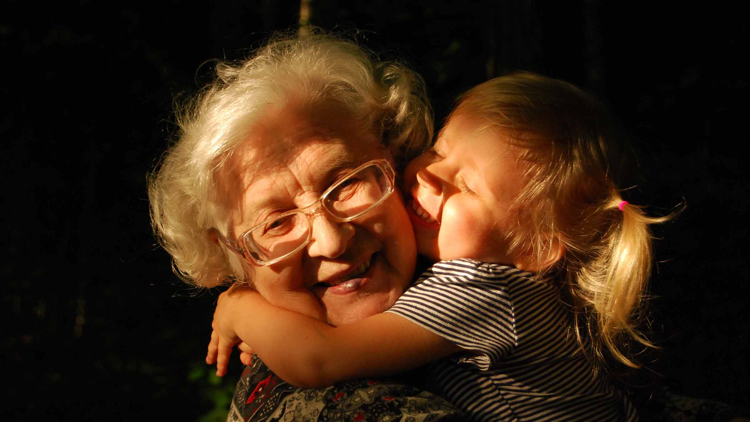 A young grandchild hugs her grandma
