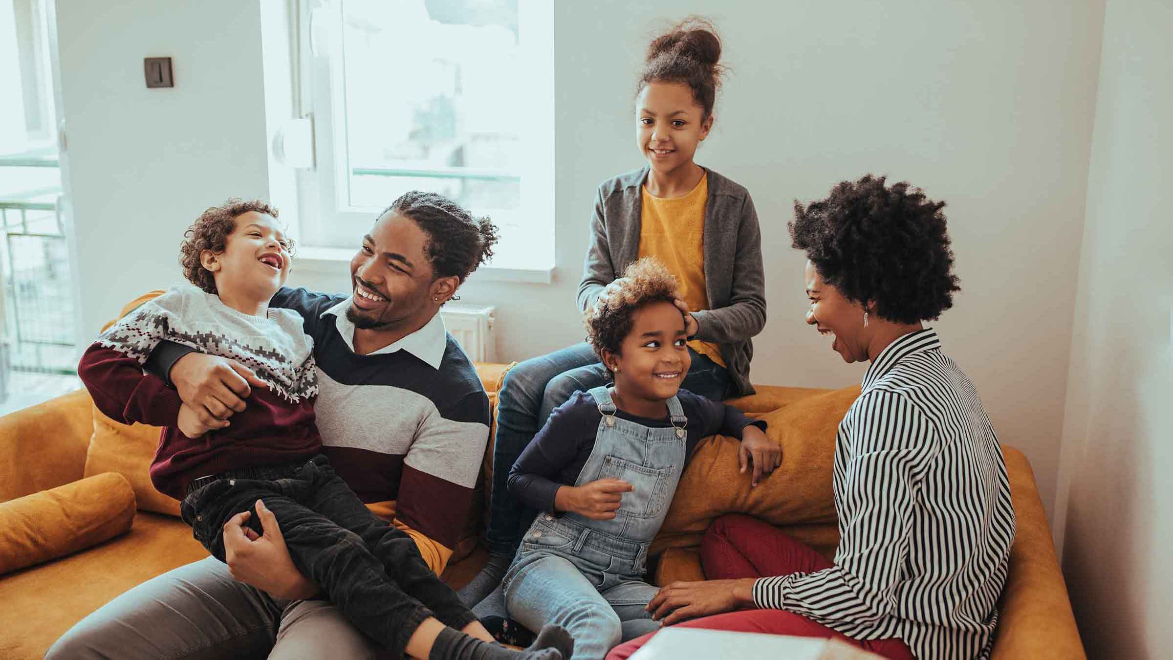 A family sits together laughing on a couch