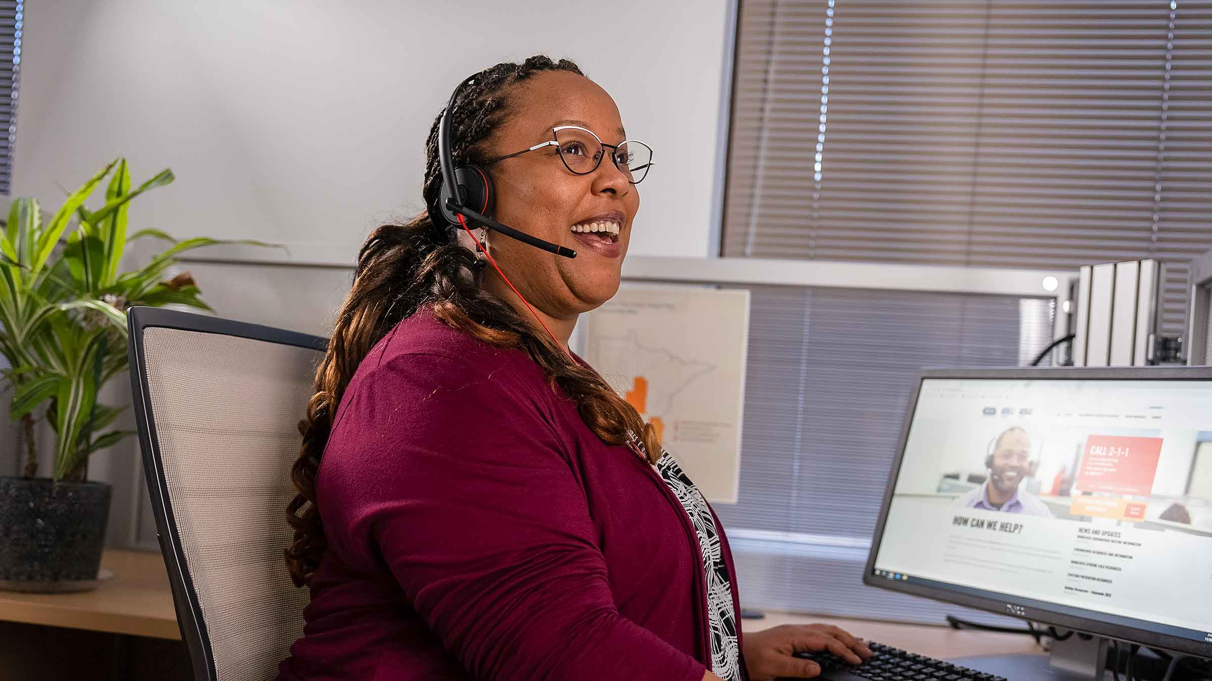 A 211 Resource Helpline Community Resource Specialist is smiling while looking off in the distance