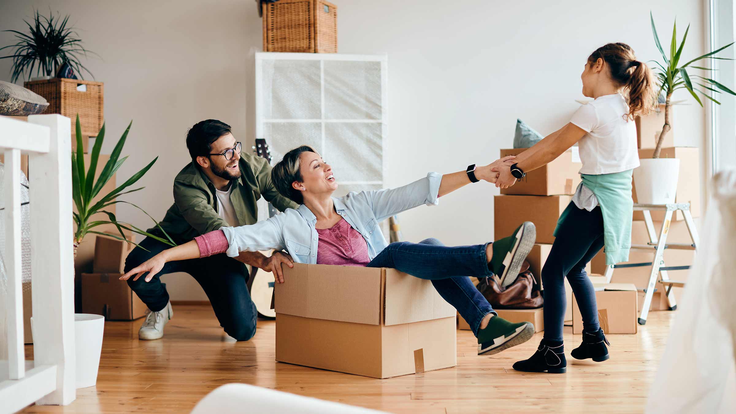 Two parents are playing with their child in a room filled with moving boxes