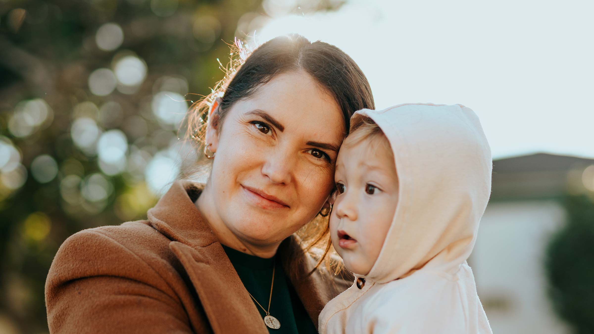 A mother holds her child and smiles at the camera