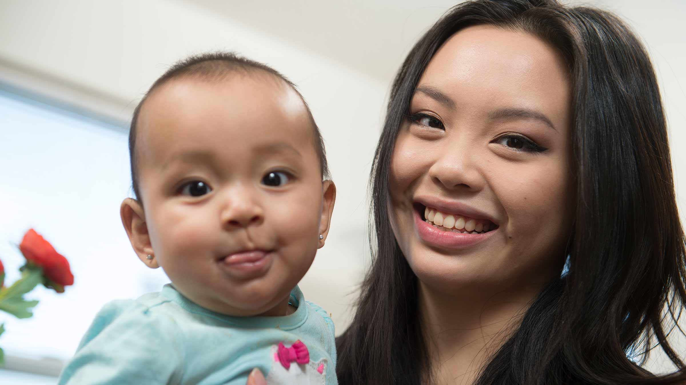 A parent and her baby are smiling at the camera