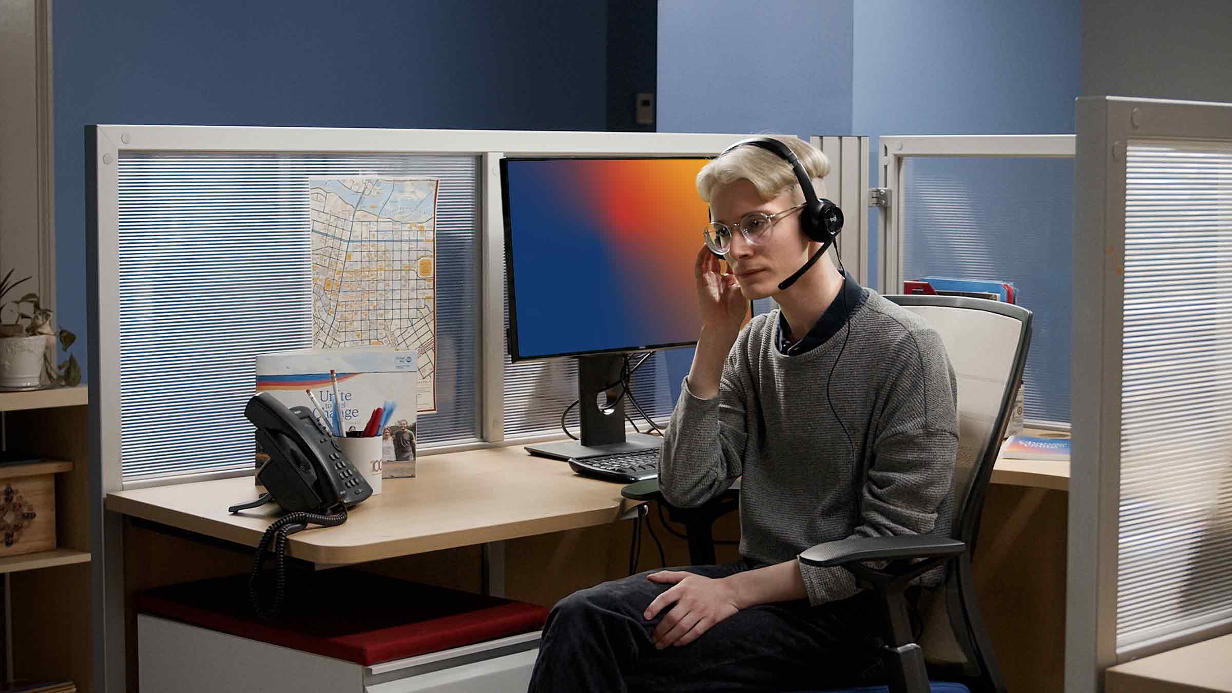 A 988 Call Specialist is answering a phone call while sitting at their desk