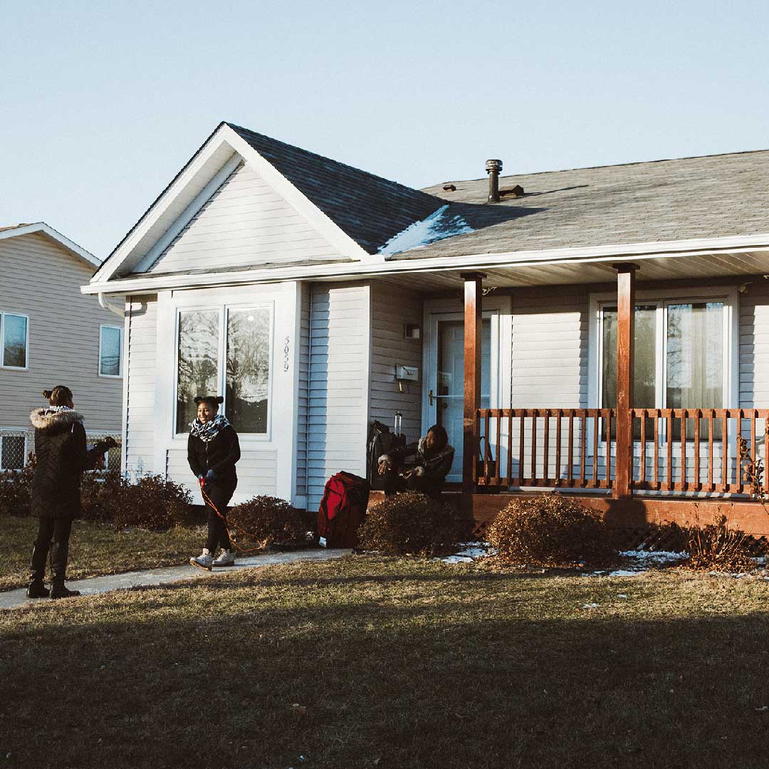 A family is hanging outside their single family home during the spring time