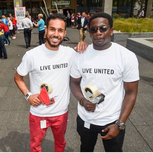 Two volunteers stand together wearing shirts that say "Live United"