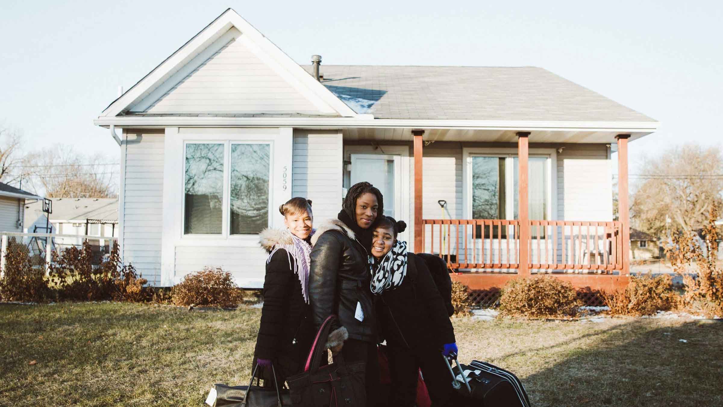 A mother and her two children stand outside their single family home