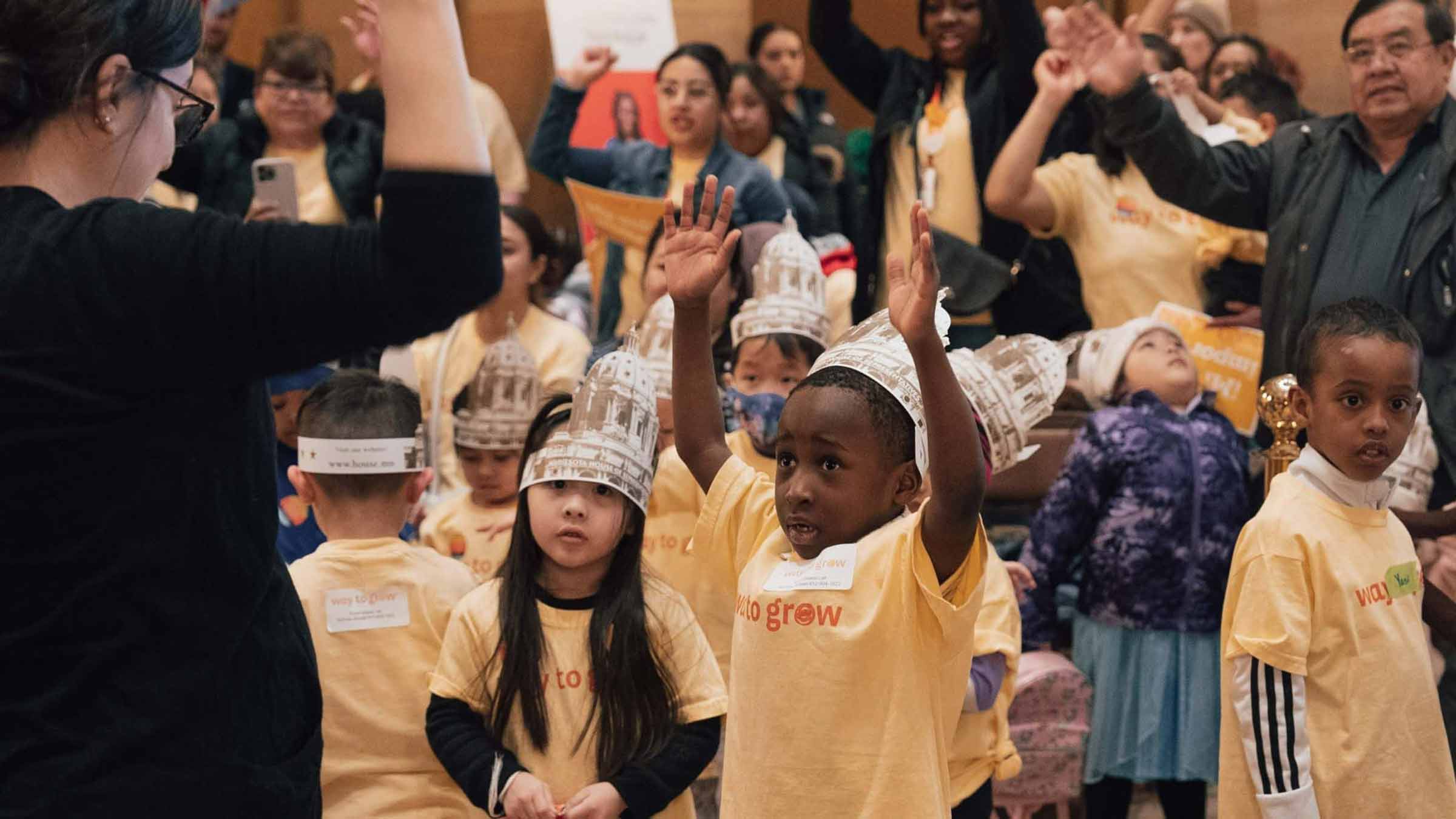 A group of young preschoolers are following the lead of a teacher during Advocacy for Children Day