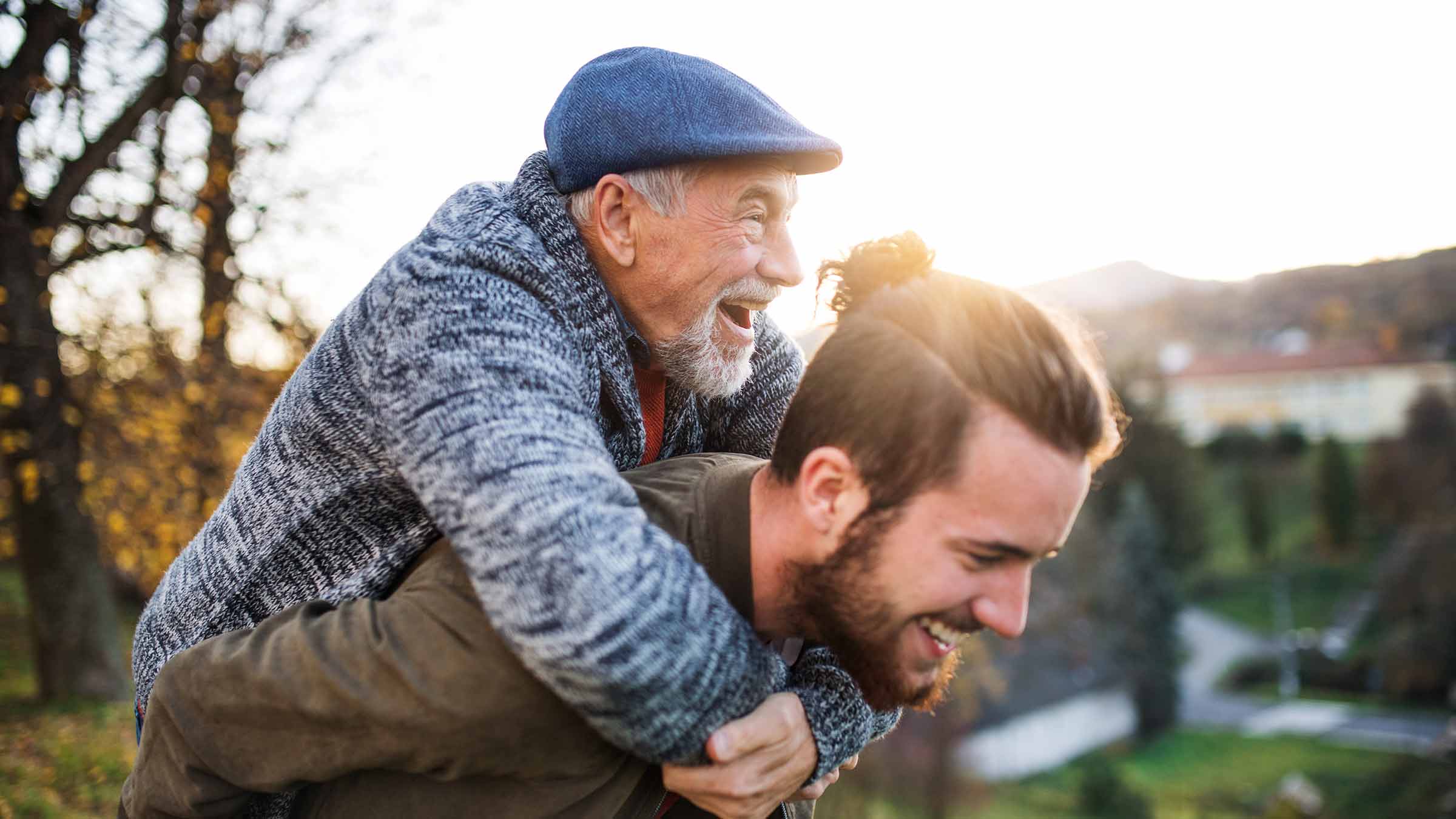 A grandpa smiles as he hugs his son