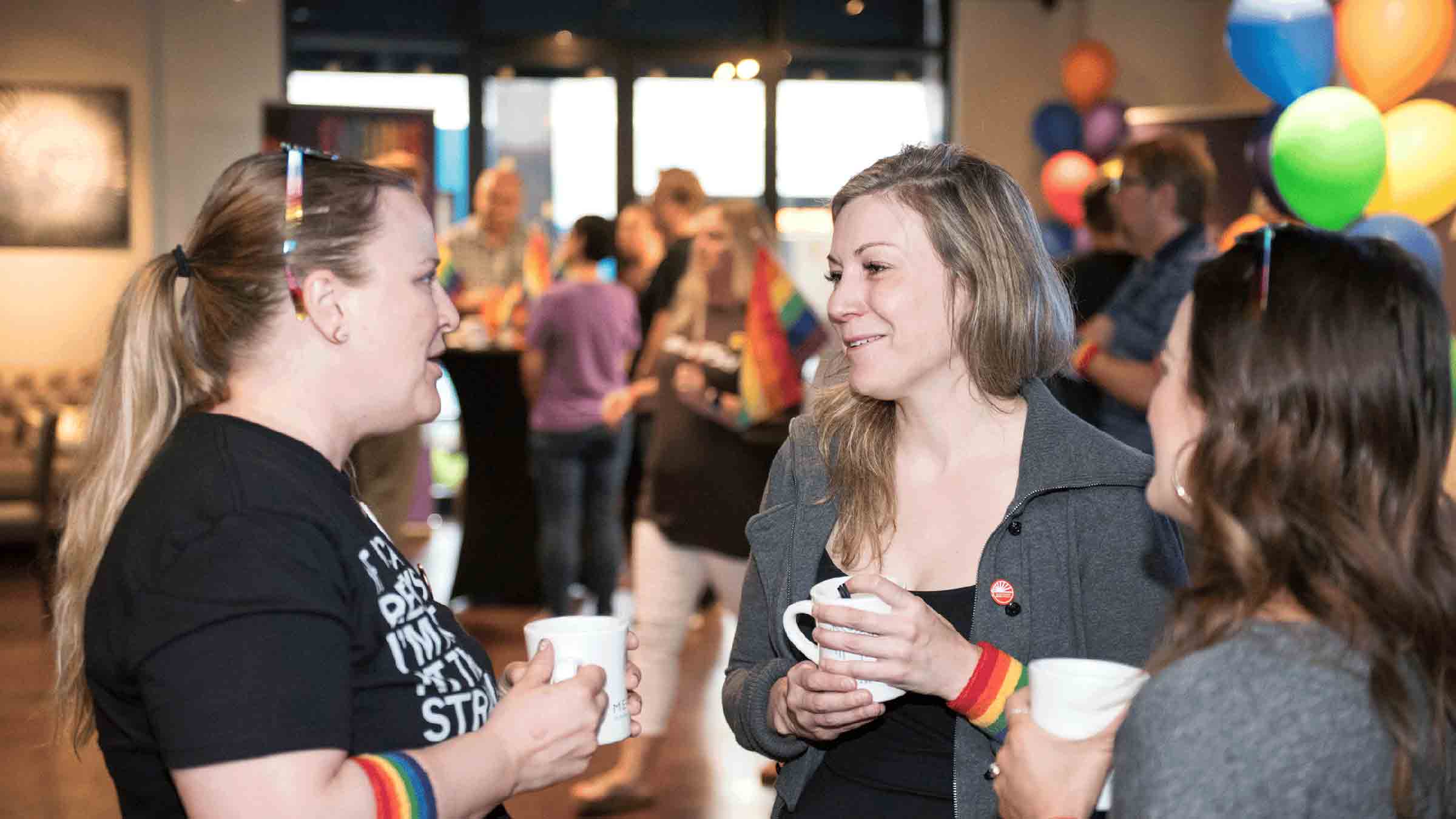 A group of giving communities members stand together talking at a networking event