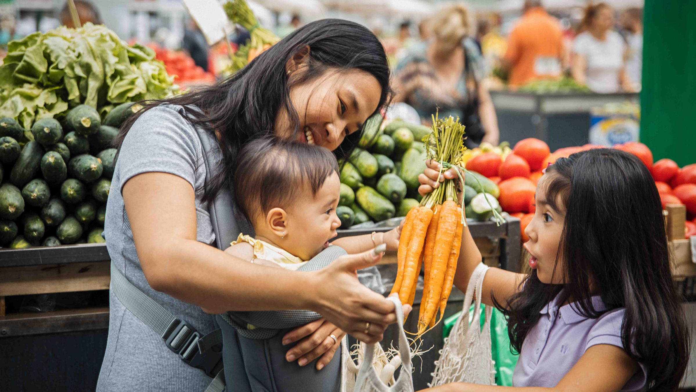 Mother and two children grocery shopping for produce.