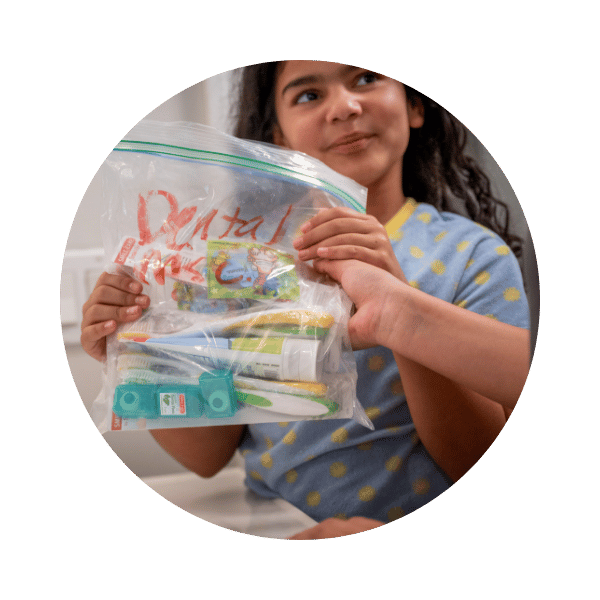 A young girl holding a hygiene pack for Home For Good.